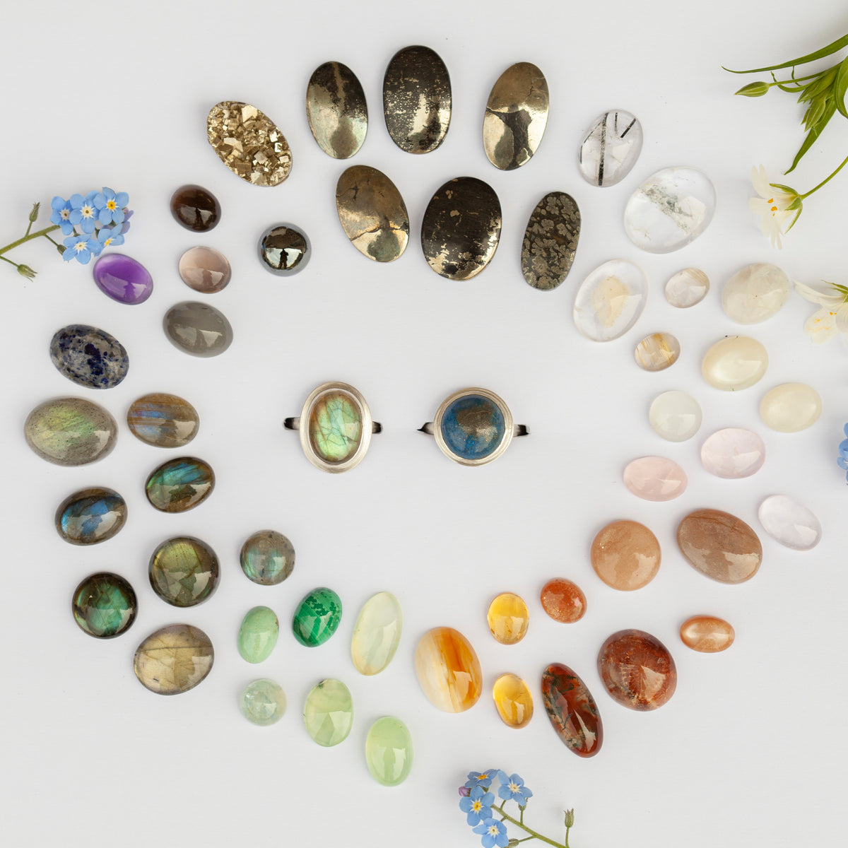 Dozens of natural stones laid out in a spiral around two silver rings