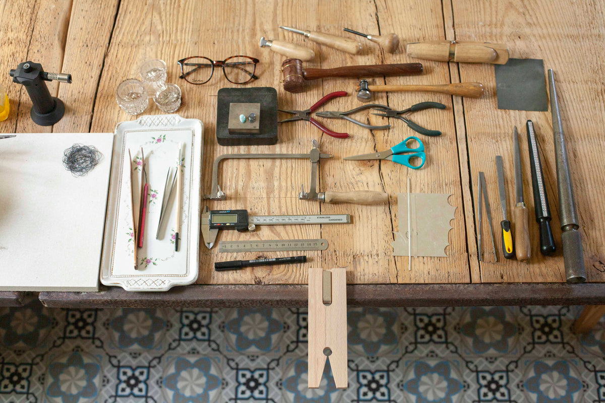 Silversmithing tools laid out on a wooden workbench